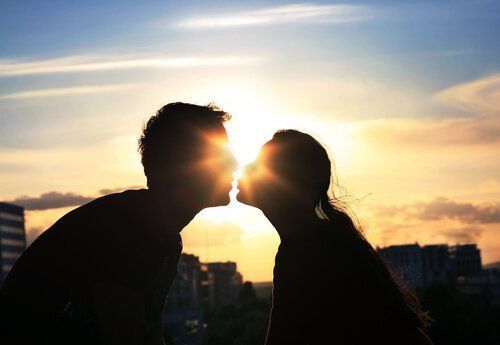 Pareja besándose a contraluz durante la puesta de sol