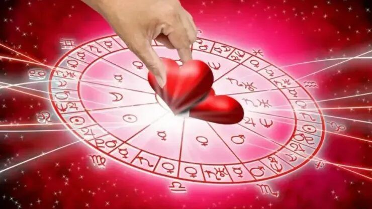 Una mano coloca un corazón rojo sobre la rueda del zodiaco