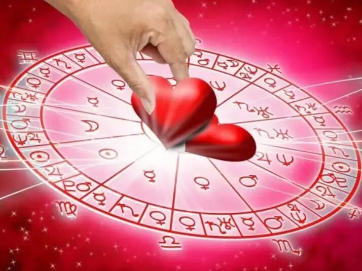 Una mano deja un corazón rojo en el centro de la carta astral