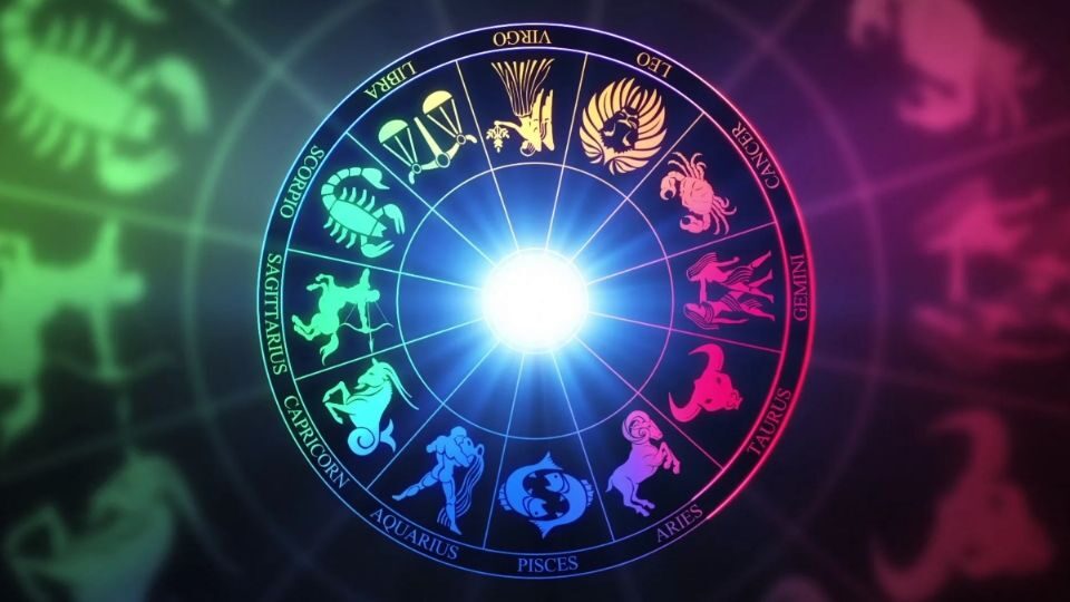 Dos manos formando un corazón sobre la rueda del zodiaco