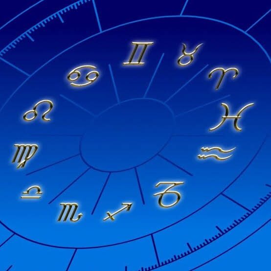 Una mano sostiene la rueda del zodiaco iluminada en azul