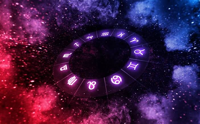Una mano coloca un corazón rojo sobre la rueda del zodiaco